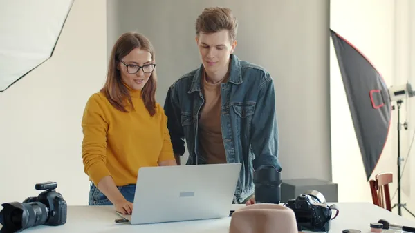 Two creators reviewing video clips on a laptop in a studio